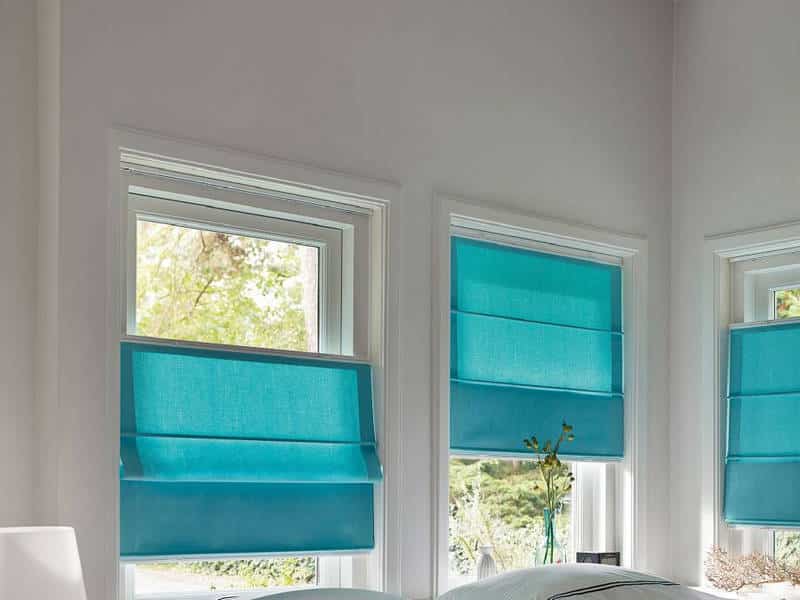 Синие римские шторы на створках пластикового окна