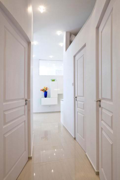 Белые двери в коридоре с блестящим полом