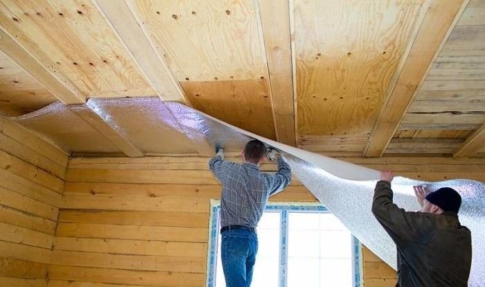 Процесс установки светоотражающего утеплителя на деревянный потолок